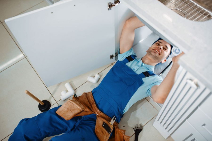 plumber-in-uniform-installing-drain-pipe-top-view-GKUZZ9Q.jpg